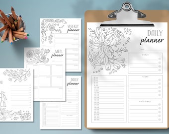 May include: A selection of monochrome printable planners, including a daily planner, weekly planner, meal planner, and to-do list. The planners feature floral illustrations and are held on a clipboard. Colour pencils are in a metal cup.