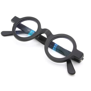 Puede incluir: Gafas redondas de marco negro con lentes tintados de azul.