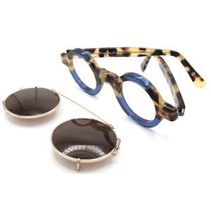 Puede incluir: Gafas con montura de carey con lentes tintados de azul y un par de gafas de sol redondas y marrones.