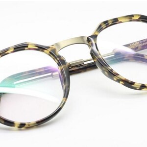 Puede incluir: Un par de gafas con montura y patillas con estampado de carey. Las monturas tienen forma redondeada con un puente dorado. Las lentes son transparentes y el nombre de la marca "ARGENTO MODERNO" es visible en la patilla.