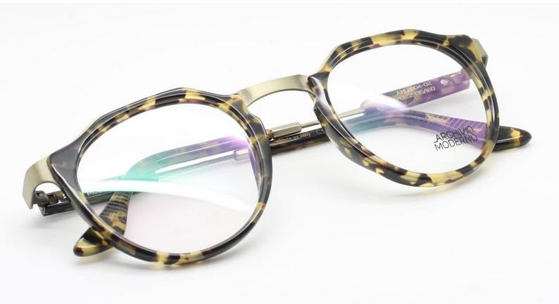 Puede incluir: Un par de gafas con montura y patillas con estampado de carey. Las monturas tienen forma redondeada con un puente dorado. Las lentes son transparentes y el nombre de la marca "ARGENTO MODERNO" es visible en la patilla.