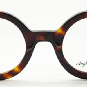 Puede incluir: Gafas redondas de carey con detalles plateados y el texto "Anglo American" en la lente derecha.