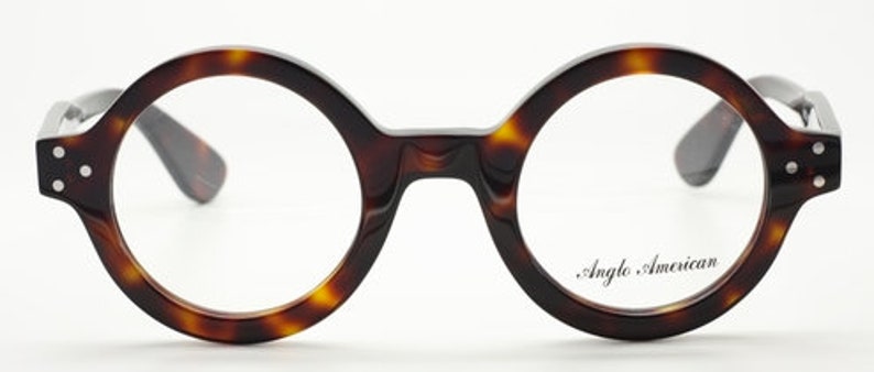 Puede incluir: Gafas redondas de carey con detalles plateados y el texto "Anglo American" en la lente derecha.