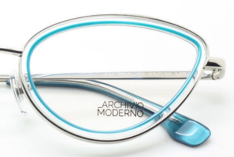 May include: Silver-toned cat-eye glasses with a blue trim around the lenses. The brand name "Archivio Moderno" is printed on the frame.