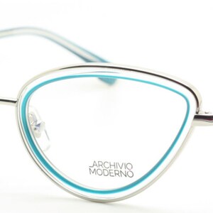 May include: Silver cat-eye glasses with a blue trim around the lenses. The brand name "ARCHIVIO MODERNO" is printed on the frame.