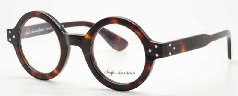 Puede incluir: Gafas redondas de carey con montura negra y lentes transparentes. El nombre de la marca "Angle. American" est&aacute; impreso en la lente derecha.