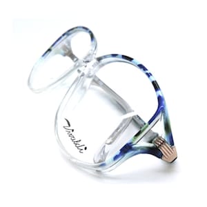 May include: Clear blue and white patterned eyeglasses with a gold accent on the side. The brand name "Vivaldi" is printed on the frame.
