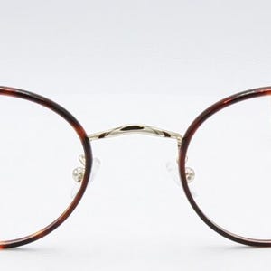 May include: Round eyeglasses with a tortoiseshell pattern on the frames. The glasses have a silver bridge and temples, and clear lenses. The design is classic and elegant, suitable for everyday wear.