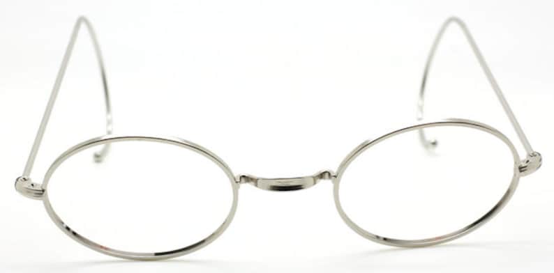 May include: Silver round-framed glasses with thin metal arms.
