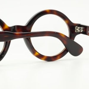 Puede incluir: Gafas redondas de carey marr&oacute;n con una patilla negra y una inscripci&oacute;n plateada que dice "masunaga optical."