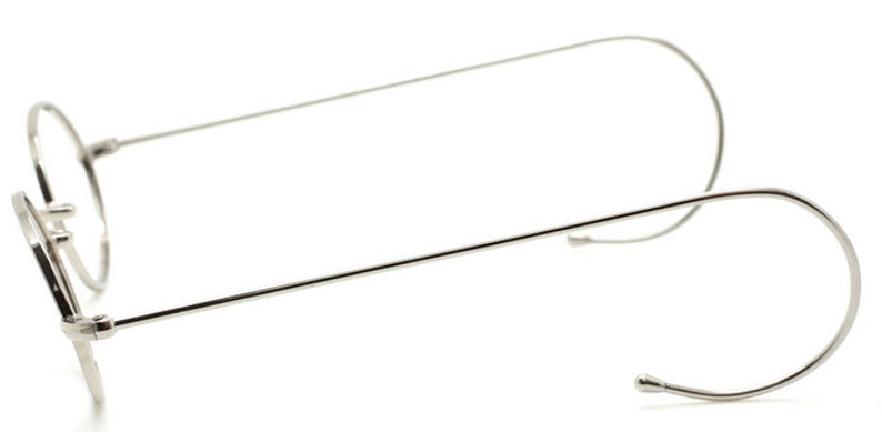 May include: Silver-toned round eyeglasses with thin metal frames and wire temple arms.