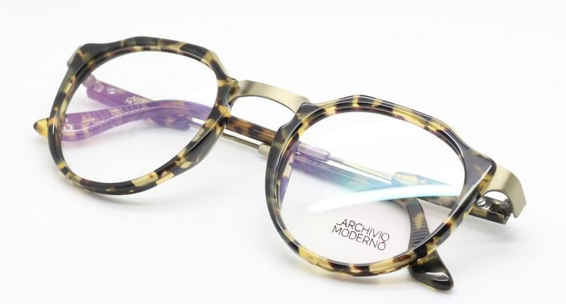 Puede incluir: Gafas redondas con montura y patillas con estampado de carey. El puente y las varillas son de color dorado met&aacute;lico. El texto "ARCHIVO MODERNO" est&aacute; impreso en la lente derecha.