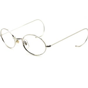 Puede incluir: Gafas redondas de montura de metal plateado con varillas finas.