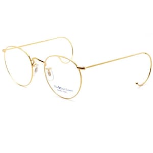 May include: Gold-tone round eyeglasses with a thin metal frame. The brand name "Vanni" is printed on the frame.
