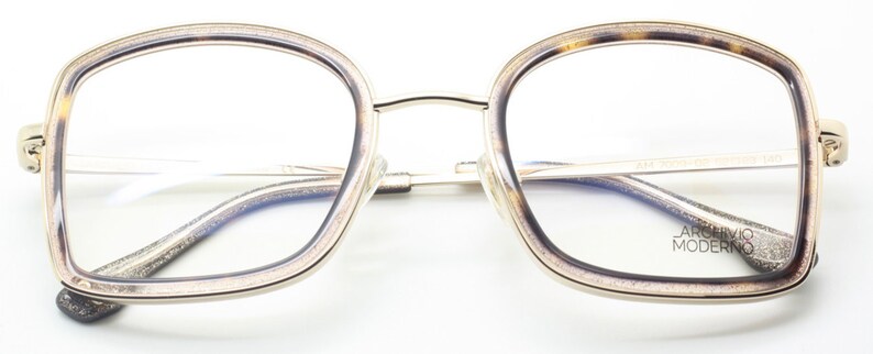 May include: Gold-rimmed eyeglasses with a tortoise shell frame. The lenses are clear and the arms are silver. The brand name "Archivio Moderno" is printed on the right arm.
