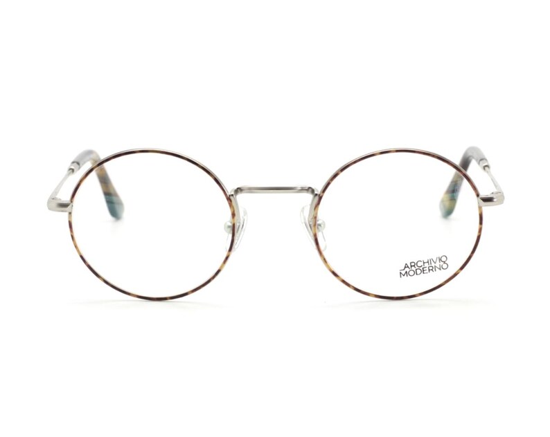 Puede incluir: Gafas redondas con montura fina plateada y estampado carey en los bordes. Las patillas tienen un dise&ntilde;o estampado. La marca "ARCHIVO MODERNO" est&aacute; impresa en la lente derecha.