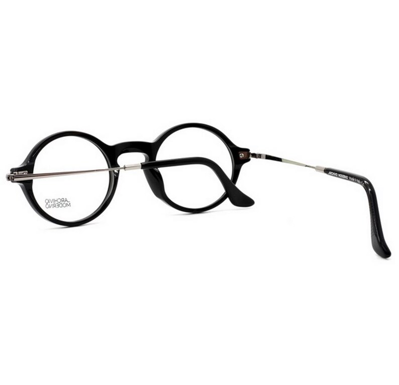 May include: Black round-frame eyeglasses with silver-tone temples. The glasses have a classic design with a keyhole bridge and curved temples for a comfortable fit. The lenses are clear, and the frame is made of a durable material.