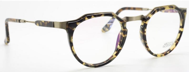 Puede incluir: Gafas con montura redonda y estampado carey. Las lentes son transparentes y el puente y las varillas met&aacute;licas tienen un acabado bronce. Las gafas tienen un dise&ntilde;o moderno y geom&eacute;trico.