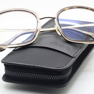 May include: Gold-rimmed tortoiseshell eyeglasses with a black leather case that says "Archivio Moderno".
