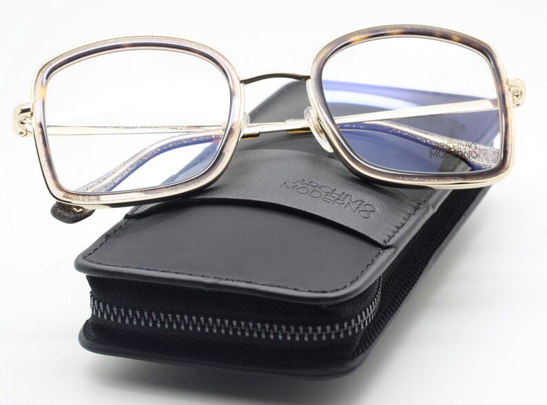 May include: Gold-rimmed tortoiseshell eyeglasses with a black leather case that says "Archivio Moderno".