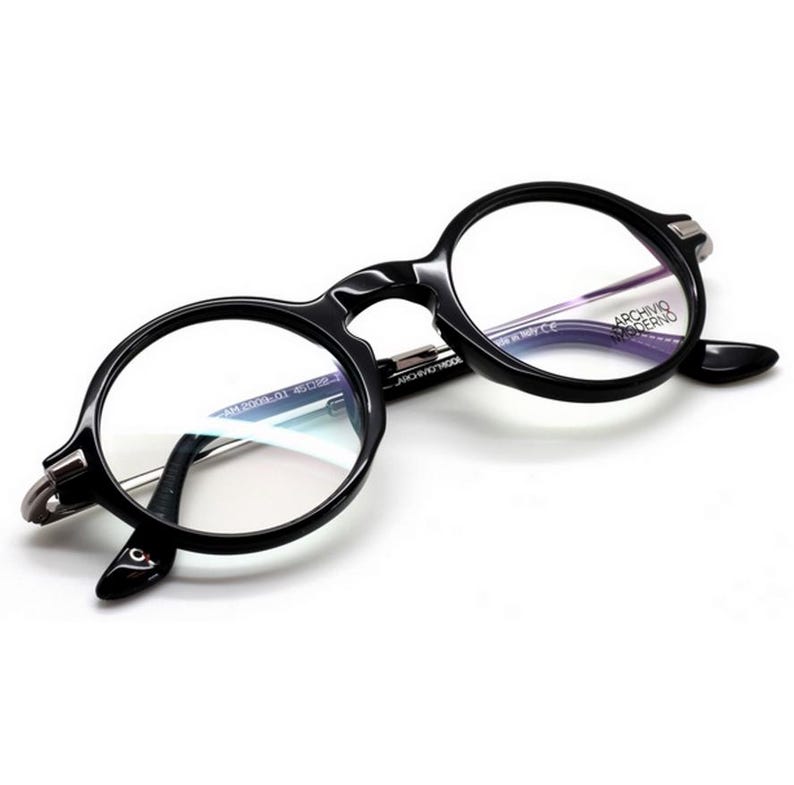 May include: Black round-frame eyeglasses with clear lenses. The glasses have a thick, glossy frame and silver-toned hinges. The brand name "ARCHIVO MODERNO" is visible on the right lens. The frame size is AM 2000A 01 45□22.