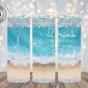 May include: Three stainless steel tumblers with a beach scene design. The tumbler on the left has the word "Name" on it. The tumbler in the middle has a sun with sunglasses on it. The tumbler on the right has the text "Drink in my hand, toes in the sand".