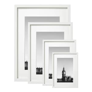 May include: Four white picture frames of different sizes, nested inside each other. The smallest frame contains a black and white photograph of a building with a clock tower.