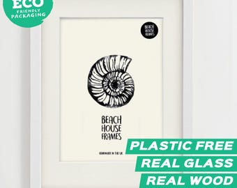 Könnte beinhalten: Ein weißer Holzbilderrahmen mit einem Druck, der eine schwarz-weiße Ammoniten-Fossil-Illustration zeigt. Der Druck enthält den Text Beach House Frames und Handmade in the UK. Ein kreisförmiges schwarzes Logo zeigt Beach House Frames.