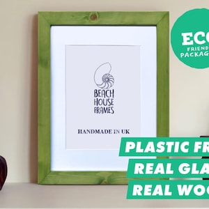 Puede incluir: Un marco de fotos rectangular con un borde de madera verde claro y un paspartú blanco. La impresión central presenta un gráfico de concha de nautilo con el texto BEACH HOUSE FRAMES y HANDMADE IN UK. Una insignia verde indica ECO FRIENDLY PACKAGING.