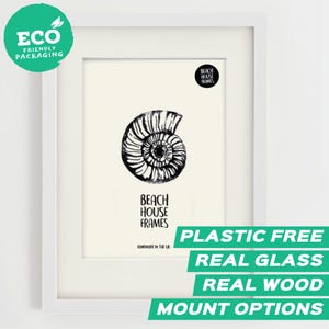 Può includere: Stampa con cornice bianca con un design a conchiglia di nautilus in bianco e nero. La cornice ha un passe-partout bianco e il testo "BEACH HOUSE FRAMES" è visibile. Testo aggiuntivo: "PLASTIC FREE", "REAL GLASS", "REAL WOOD" e "MOUNT OPTIONS".