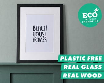 Könnte beinhalten: Ein schwarzer Holzbilderrahmen mit weißem Passepartout und einem weißen Druck mit dem schwarzen Text BEACH HOUSE FRAMES. Der Rahmen ist mit echtem Glas ausgestattet und in umweltfreundlichen, plastikfreien Materialien verpackt.