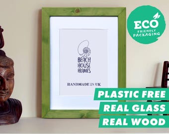 Puede incluir: Un marco de fotos rectangular con borde de madera verde claro y paspartú blanco. La impresión central muestra un gráfico de concha de nautilo con el texto BEACH HOUSE FRAMES y HANDMADE IN UK. Una insignia verde dice ECO FRIENDLY PACKAGING.