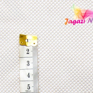 Pode incluir: Tecido de malha branca com uma fita métrica mostrando 5 polegadas. O tecido tem um padrão de diamante. O texto "Jagazi Naturals" é visível no canto superior direito da imagem.
