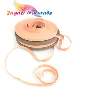 May include: A close-up of two rolls of peach-coloured cotton webbing, with one roll on top of the other. The rolls are on a white surface. The text "Jagazi Naturals" is visible in the background.