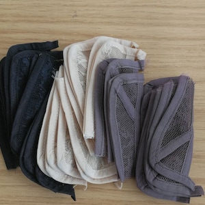 May include: Three stacks of black, beige, and grey mesh fabric. The fabric is folded and has a textured surface.