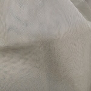 May include: White sheer fabric with a fine mesh texture. The fabric is draped and has a soft, flowing appearance.