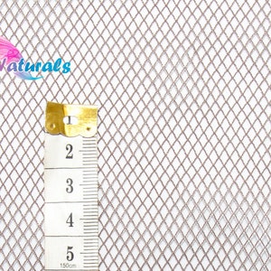 Pode incluir: Um tecido de malha metálica prateada com um padrão de diamante. Uma régua é colocada sobre o tecido para mostrar a escala. A régua mede 12,7 cm.