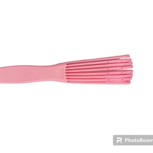 Könnte beinhalten: Eine rosa Plastik-Entwirrbürste mit einem breiten Griff und mehreren Reihen flexibler Zähne.