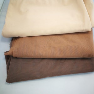 Puede incluir: Tres piezas de tela apiladas una encima de la otra. La pieza superior es de color beige claro, la pieza del medio es de color marrón claro y la pieza inferior es de color marrón oscuro.