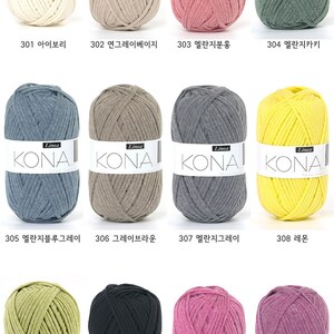 May include: A collection of 12 yarn skeins in various colors, including ivory, beige, pink, green, blue, gray, yellow, lime green, black, and purple. Each skein has the word "KONA" printed on the label.