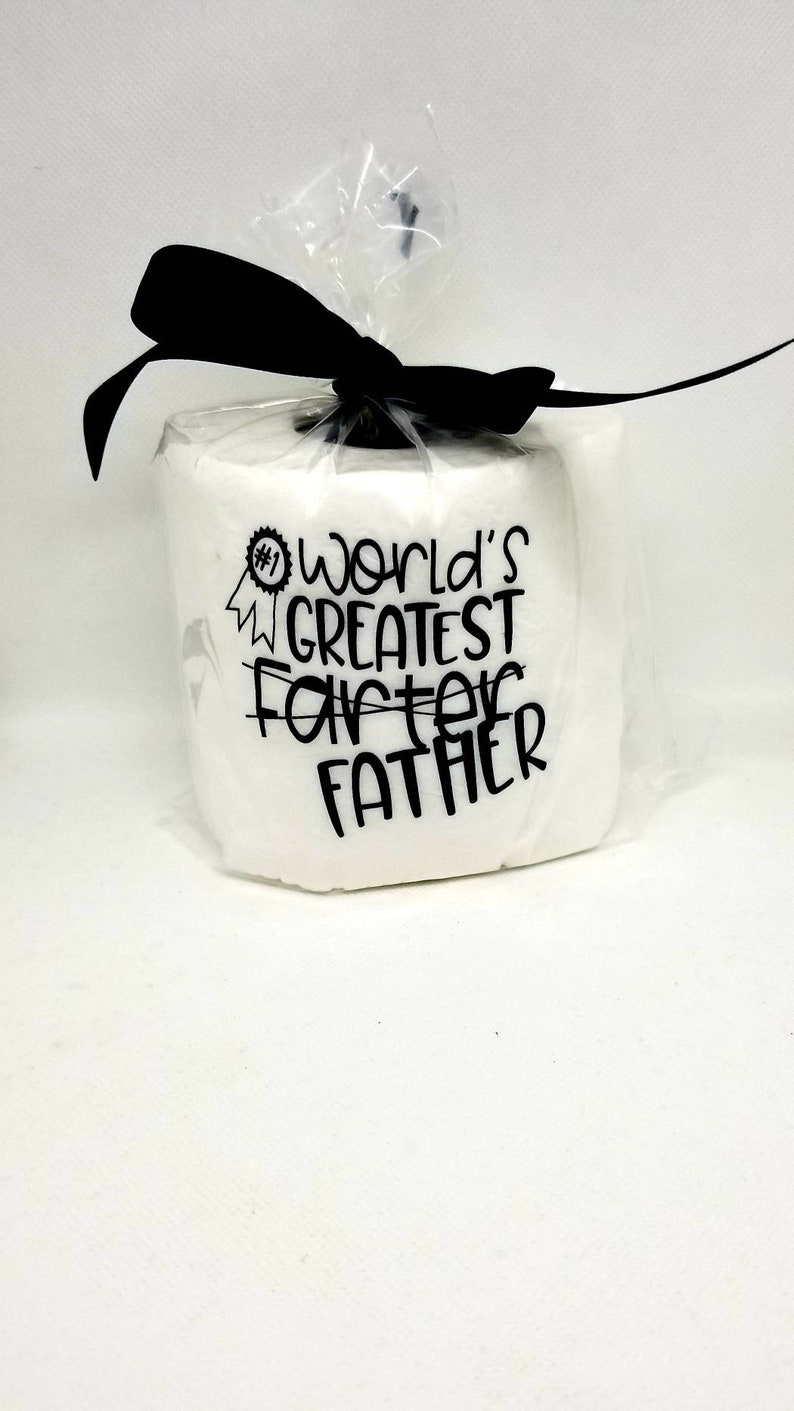May include: A white gift wrapped in clear cellophane and tied with a black ribbon. The gift has the text "#1 World's Greatest Father" in black lettering.