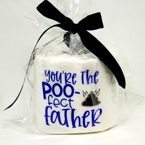 May include: A white toilet paper roll wrapped in clear cellophane and tied with a black bow. The roll has blue text that reads "You're The POO-fect FATHER" with a graphic of a pile of poop.