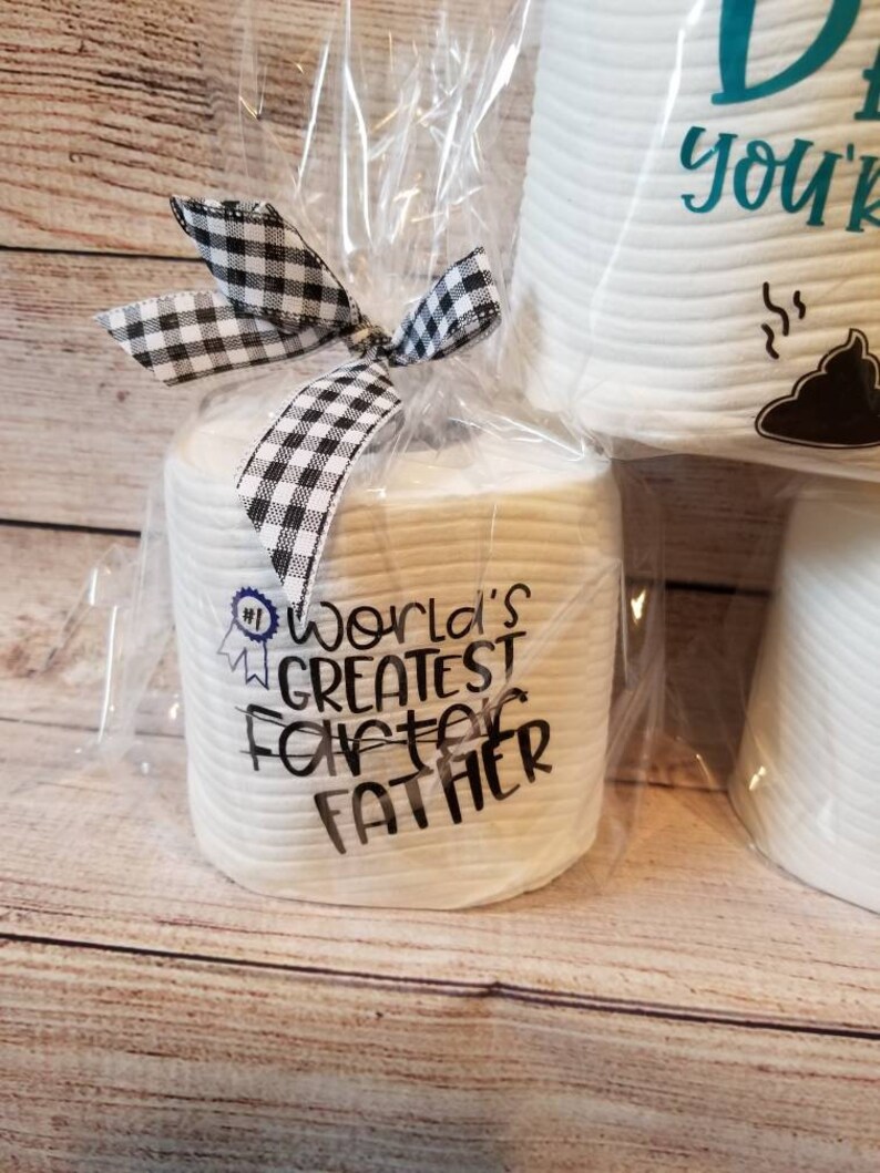 May include: A gift set of white toilet paper rolls wrapped in clear cellophane and tied with a black and white checkered bow. One roll is printed with "World's Greatest Farter Father".