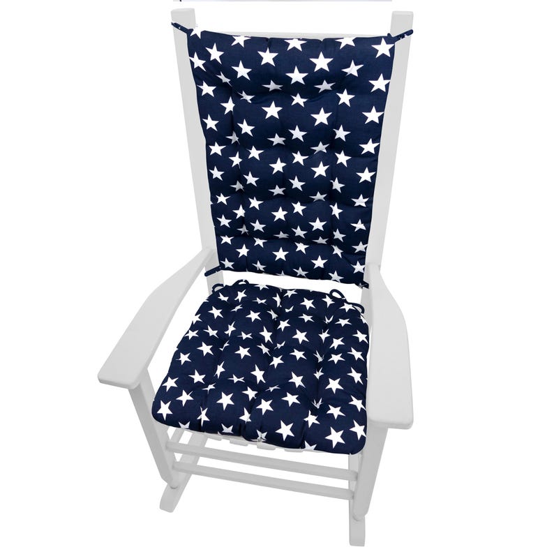 Op de afbeelding: Een witte schommelstoel met marineblauwe kussens. De kussens hebben een patroon van witte sterren. De stoel is ontworpen voor buitengebruik. De kussens zijn met banden aan de stoel bevestigd. Klassiek ontwerp.