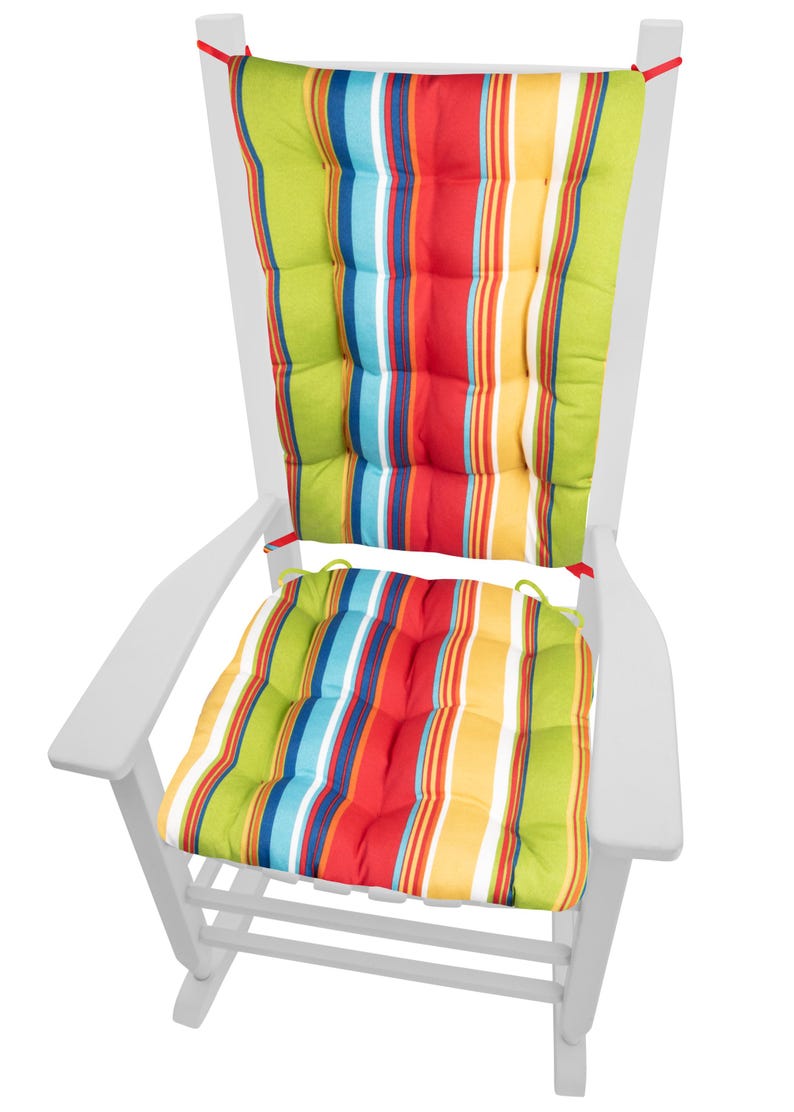 Op de afbeelding: Witte houten Adirondack stoel met kleurrijke gestreepte kussens. De kussens hebben verticale strepen in groen, rood, geel, blauw en wit. De stoel is ontworpen voor gebruik buitenshuis.