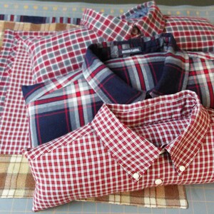 May include: A stack of four plaid shirts, sewn together to create a pillow. The pillow is red, white, and blue plaid. The shirts are all different sizes and patterns.