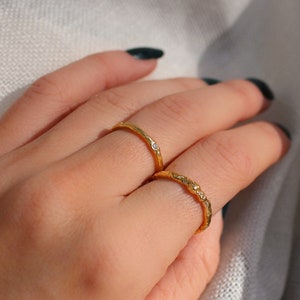 Peut inclure: Deux bagues en or avec un design texturé et de petites pierres claires sur un doigt.