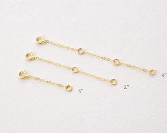 Puede incluir: Tres cadenas extensoras de joyería de metal color oro de diferentes longitudes. Las cadenas tienen texto que indica longitudes de 1 pulgada, 2 pulgadas y 3 pulgadas. Cada cadena cuenta con un pequeño cierre circular en un extremo.