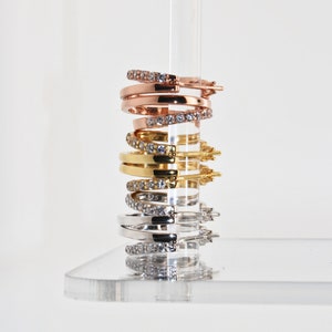 K&ouml;nnte beinhalten: Ein Stapel von vier Creolen mit Zirkonia-Steinen. Die Ohrringe sind in verschiedenen Metalloberfl&auml;chen: Ros&eacute;gold, Gold und Silber.