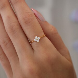 May include: A gold ring with a cluster of small, clear stones set in a flower shape.